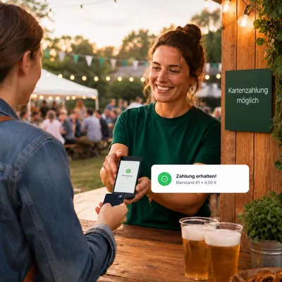 Helferin am Getränkestand eines Vereinsfests nimmt eine Kartenzahlung mit dem Smartphone entgegen
